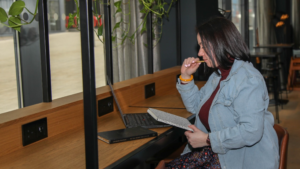Why everyone needs Google Business Profile, text on an imag eof Gemma loking at the laptop with a notebook in one hand and pen in another